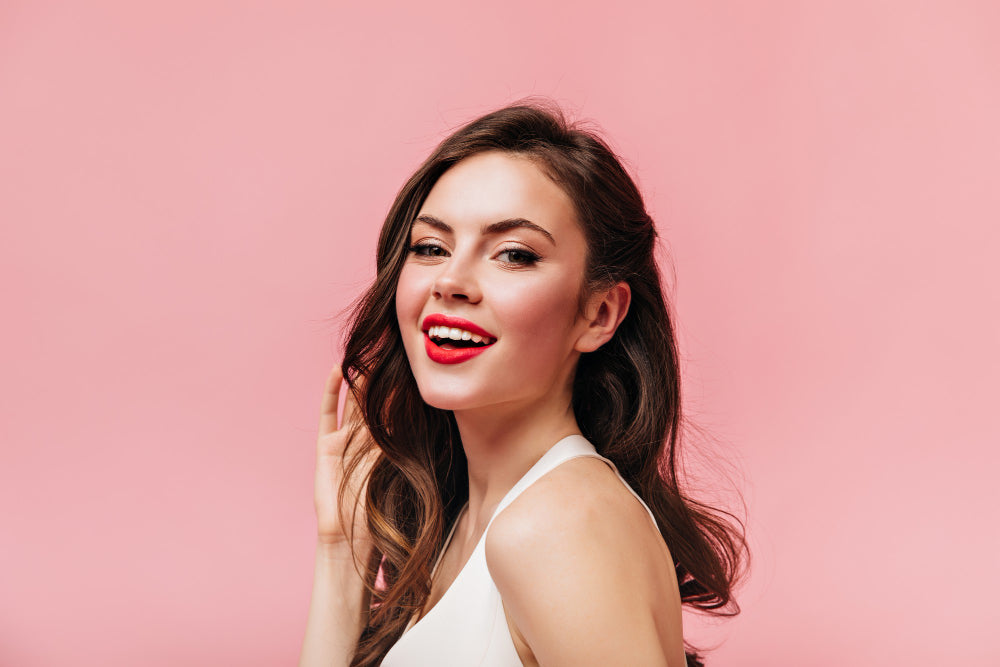 modelo de cabello castaño y labios rojos sonriendo con su maquillaje cuidado frente a la lluvia