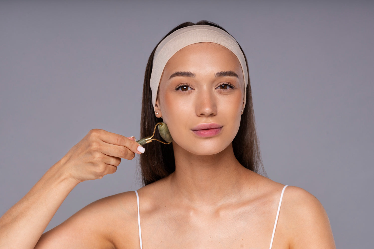 una modelo haciendo su skincare donde nos muestra cómo usar un face roller o rodillo facial de jade