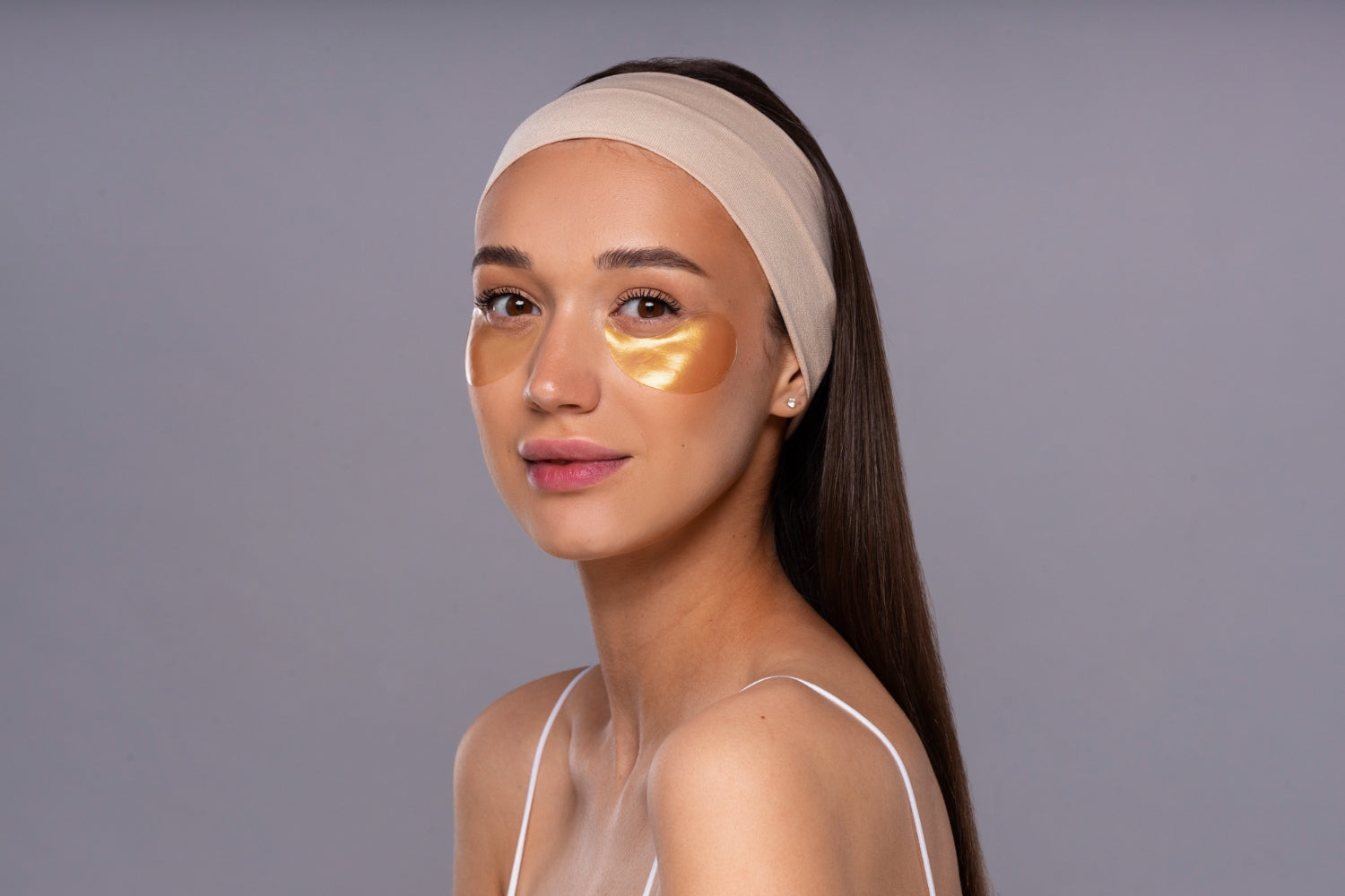 una bella modelo morena utilizando una mascarilla de oro en su gold facial