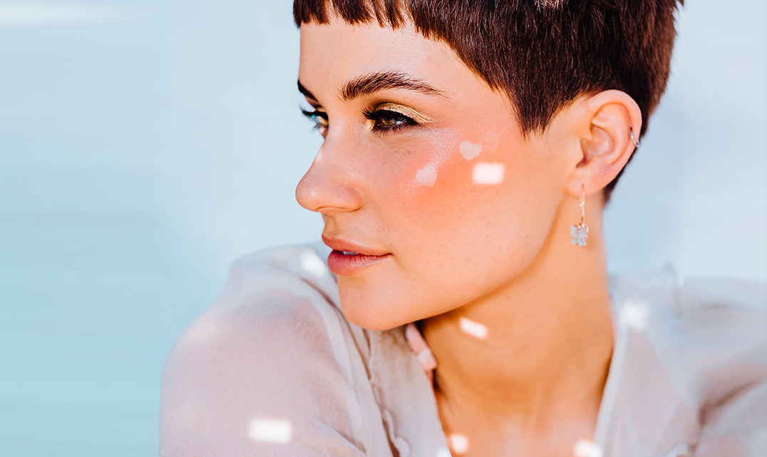 una chica joven con un corte pixie luciendo su maquillaje con glitter
