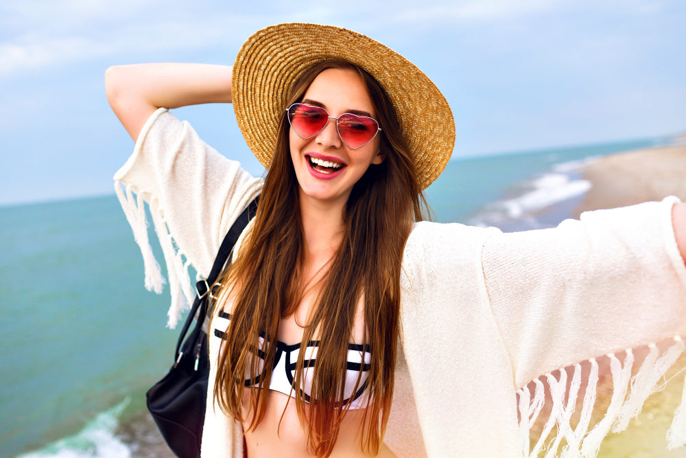 mujer joven y feliz en la playa sin perder su toque en el verano gracias a OnPost