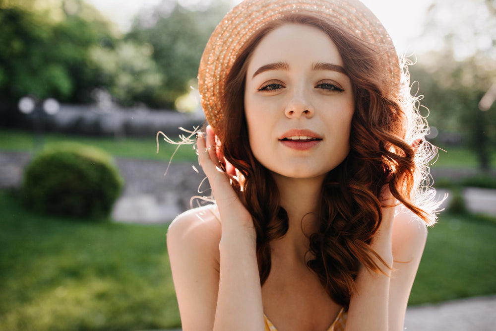 una modelo en un parque mostrando su piel con poco maquillaje por utilizar productos de cosmética natural que cuidan el ambiente