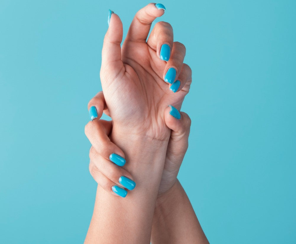 un manicure de uñas de sirena con un azul océano y un fondo azul que muestra el mar en las manos